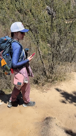 Hiker checks phone on mountain trail in Nepal