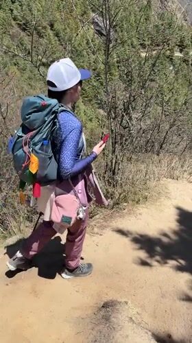 Hiker checks phone on mountain trail in Nepal