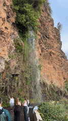 Tourists gather at roadside waterfall in Ponta do Sol