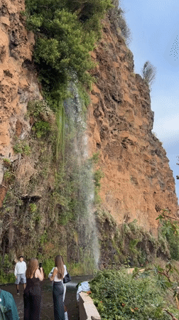 Tourists gather at roadside waterfall in Ponta do Sol