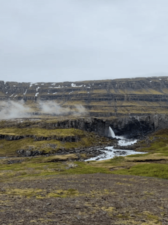 Tourist documents Icelandic waterfall and mountain landscape