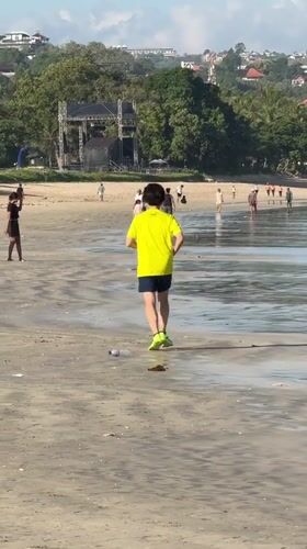 Early morning beach activities in Kuta: jogger, boat launches