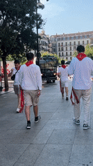 San Fermín street scenes: red scarves, blue parade groups, brass band