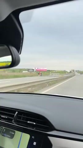 The video shows a car driving on a highway. On the right side of the road is a blue sign indicating the border of Istanbul Province in Turkey. The sky is overcast, and the surrounding landscape consists of fields and some buildings in the distance. The video is taken from the driver's perspective, showing the car's dashboard and windshield.