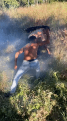 Two men deal with smoke in grassy area