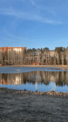 Frozen lake reflects sunlight near flagged building in Russia