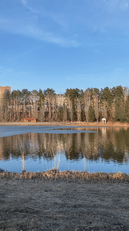 Frozen lake reflects sunlight near flagged building in Russia