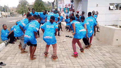 Young adults perform traditional dance in matching commemorative shirts