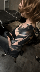 Woman with tattoo sits with smartphone in Moscow