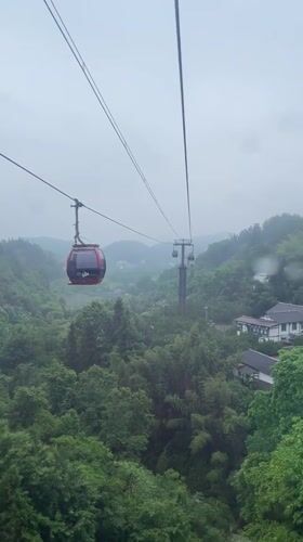 Cable cars navigate misty mountains during rainfall in Yongding District