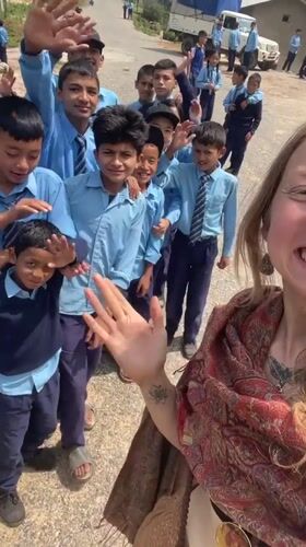 Woman films selfie with schoolboys in Budar, Nepal