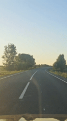 Vehicle travels curved road in Perevoznoe during low sun