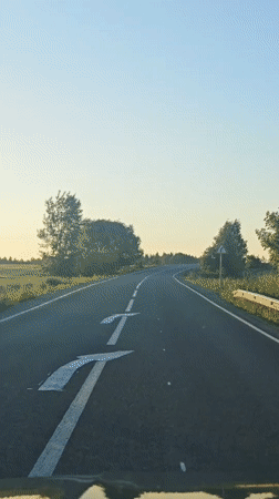 Vehicle travels curved road in Perevoznoe during low sun