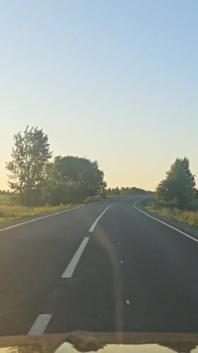 Vehicle travels curved road in Perevoznoe during low sun