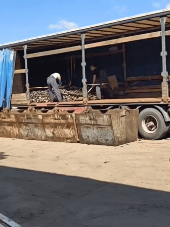 Workers unload truck materials into containers in Noviy