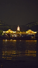 Evening crowds gather around illuminated West Lake boats in Hangzhou