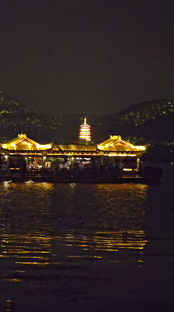 Evening crowds gather around illuminated West Lake boats in Hangzhou