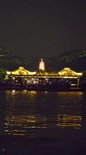 Evening crowds gather around illuminated West Lake boats in Hangzhou