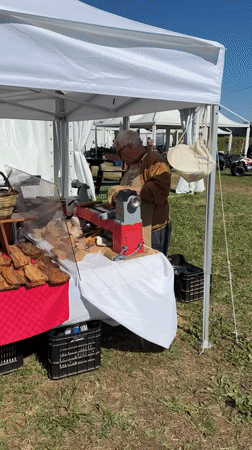 Woodworker demonstrates lathe techniques at outdoor event in Aprilia