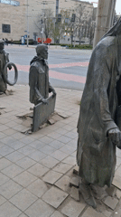 Bronze figures emerge from sidewalk in Wrocław's Passage monument
