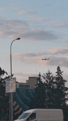 Plane passing over a quiet Prague street on a cloudy afternoon