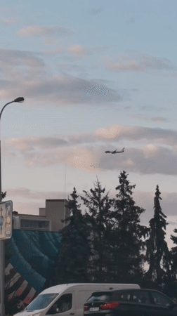 Plane passing over a quiet Prague street on a cloudy afternoon