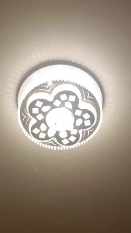 The video shows a ceiling light fixture being switched through different color settings. The light is round and has a decorative pattern with a central bulb. The color of the light changes from cool white to warm white and back again. The ceiling is plain and light beige.