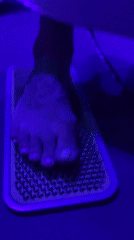 Person stands on nail bed at neon-lit party