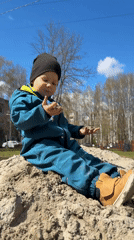 Child plays in sand pile under clear skies in Yaroslavl