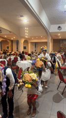 Traditional folk procession with floral headdresses inside a Sicilian banquet hall