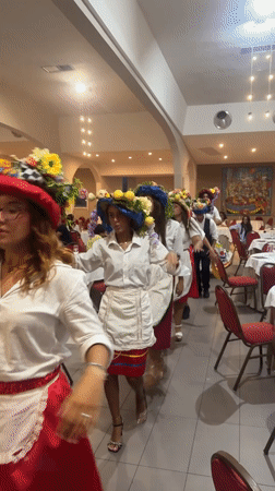 Traditional folk procession with floral headdresses inside a Sicilian banquet hall