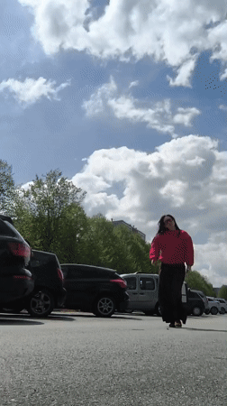 Woman in red sweater enjoys sunny morning in Riga parking lot