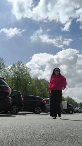 Woman in red sweater enjoys sunny morning in Riga parking lot