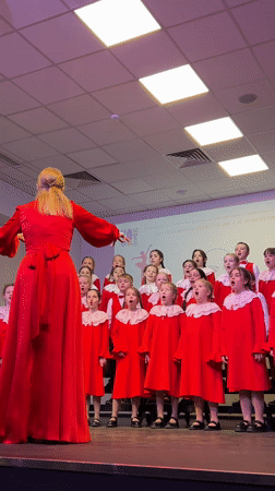 Children's choir performs in red dresses at Moscow auditorium