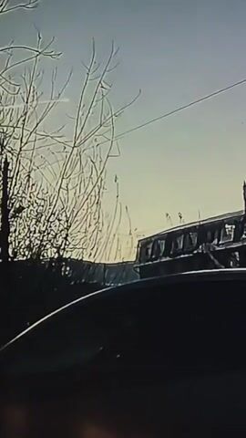 The video captures a view from inside a vehicle, looking out at a cloudy sky and a building. The building appears to be undergoing some form of construction or renovation, with scaffolding visible. Bare tree branches frame the left side of the image. A power line stretches across the sky. The overall mood is somewhat bleak, perhaps due to the overcast weather. The specific location is Homyel, Belarus. No text is visible in the video.