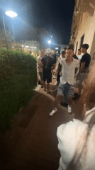 Young people gather for nighttime social activities near illuminated Ferris wheel