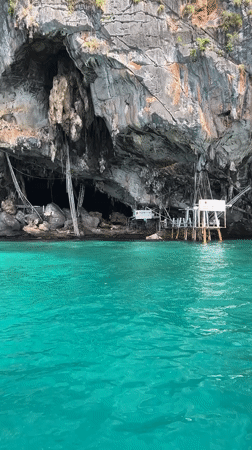Sea cave entrance in Ao Nang's limestone cliffs, approached by boat
