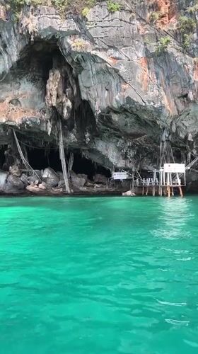Sea cave entrance in Ao Nang's limestone cliffs, approached by boat