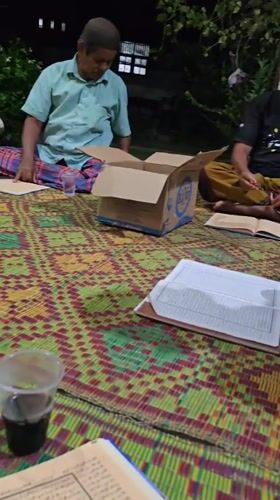Outdoor evening reading circle on woven mats in rural Indonesia