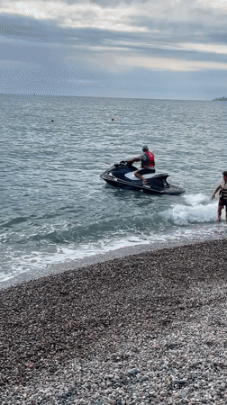Sochi beach day: jet skis, pebble shore, and colorful street umbrellas