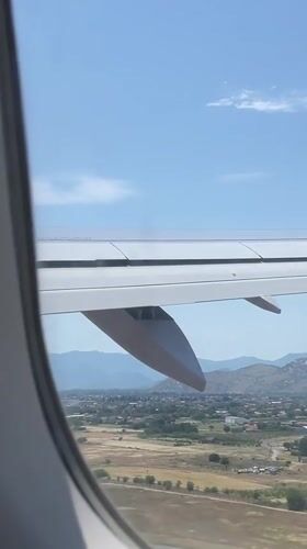 Aircraft passenger observes wing and landscape over Golubovci, Montenegro