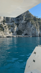 Boat travels Capri coastline on clear morning