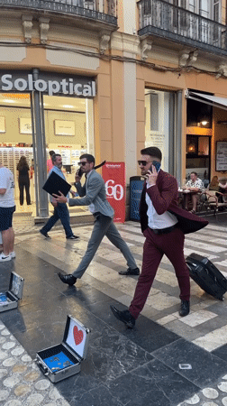 Suited duo crosses Málaga pedestrian street, phones in hand