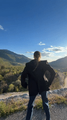 Woman celebrates on hilltop overlooking valley in Montenegro