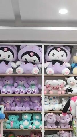 The video shows a large collection of stuffed animals displayed on shelves in a store. The stuffed animals include various characters such as purple bears, rabbits, foxes, cows, sheep, yellow chicks, elephants, and cats. The shelves are organized by size and type of animal, with larger stuffed animals on the upper shelves and smaller ones on the lower shelves. The lighting in the store appears to be bright and even, suggesting artificial lighting. There are no people visible in the video.