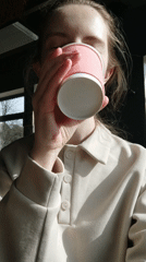 Woman enjoys morning drink by window during quiet moment