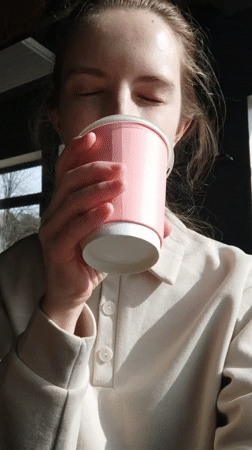 Woman enjoys morning drink by window during quiet moment