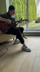 Young guitarist plays red acoustic guitar indoors in Kursk