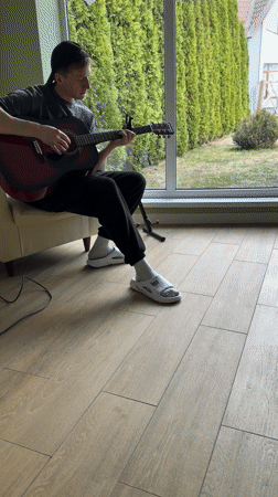 Young guitarist plays red acoustic guitar indoors in Kursk