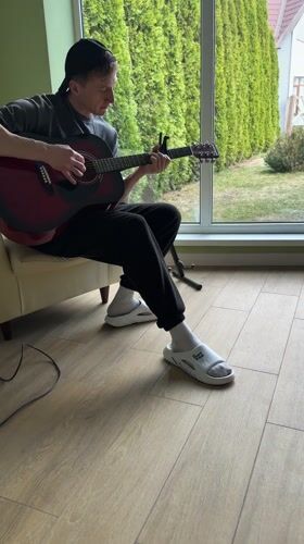 Young guitarist plays red acoustic guitar indoors in Kursk